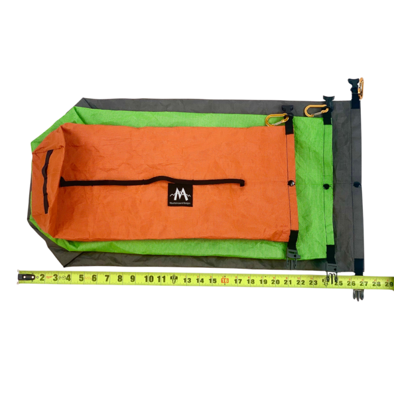 A large gray, medium lime, and small orange Dry Bag lay flat next to a measuring tape showing size