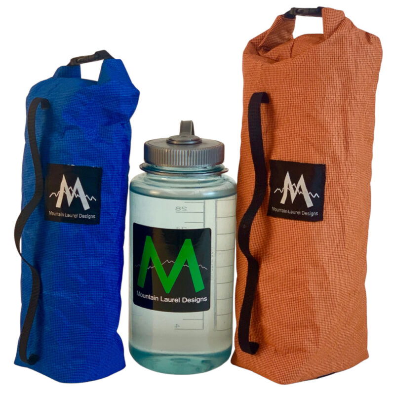 A 1.6L Electric Blue Dry Fork Bag (left) and a 2.5L Rust Orange Dry Fork Back (right) sit next to a water bottle